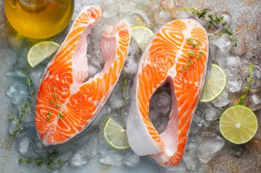 İki ham taze somon veya alabalık biftek buz, kireç, kekik ve zeytinyağı paslı mavi bir arka plan üzerinde ile omega-3 yağ açısından zengin. Sağlıklı ve diyet gıda. Üstten görünüm. Düz yatıyordu.