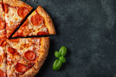 Lezzetli biberli pizza ve siyah beton arka planda domates fesleğeni. Acı biberli pizzanın en iyi manzarası. Metin için kopyalama alanı ile. Düz yatıyordu.