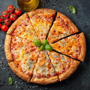 Fesleğen, domates ve karanlık bir beton masaya zeytin yağı ile lezzetli İtalyan pizza dört peynir. Üstten görünüm kopya alanı ile. Düz yatıyordu.