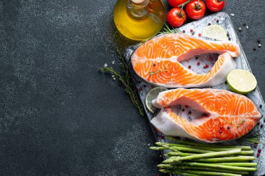 İki ham taze somon veya alabalık biftek, kireç, kekik ve Zeytinyağı karanlık bir arka plan ile omega-3 yağ açısından zengin. Sağlıklı ve diyet gıda. Üstten görünüm kopya alanı ile. Düz yatıyordu