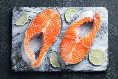 İki ham taze somon veya alabalık biftek, kireç, kekik ve Zeytinyağı karanlık bir arka plan ile omega-3 yağ açısından zengin. Sağlıklı ve diyet gıda. Üstten görünüm. Düz yatıyordu