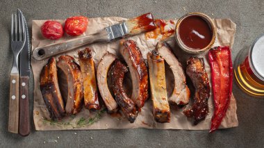 Domuz kaburga closeup Barbekü soslu ızgara ve bal karamelize. Lezzetli Aperatif karanlık beton zemin üzerinde doldurmak için bir kağıt üzerinde bira için. Üstten görünüm. Düz yatıyordu.