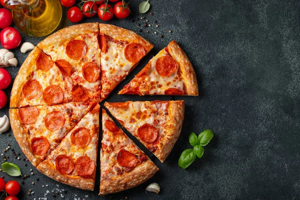 Leckere Pfefferoni-Pizza und Kochzutaten Tomaten Basilikum auf schwarzem Betongrund. Blick von oben auf die Chili-Pizza. Mit Kopierraum für Text. Flache Lage — Stockfoto