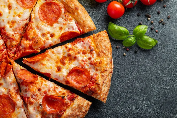 Leckere Pfefferoni-Pizza und Kochzutaten Tomaten Basilikum auf schwarzem Betongrund. Blick von oben auf die Chili-Pizza. Mit Kopierraum für Text. Flache Lage — Stockfoto