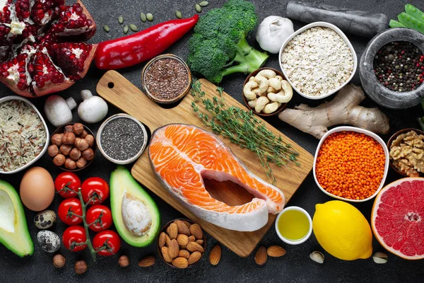 Auswahl an gesunden Lebensmitteln: Fisch, Obst, Nüsse, Gemüse, Samen, Superfood, Getreide, Blattgemüse auf schwarzem Betongrund. flache Lage — Stockfoto