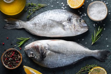 İki taze çiğ Dorado balık baharat ve karanlık bir taş masaya zeytin yağı ile. Üstten görünüm. Düz yatıyordu.