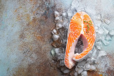 ham taze somon veya alabalık biftek buz, kireç, kekik ve zeytinyağı paslı mavi bir arka plan üzerinde ile omega-3 yağ açısından zengin. Sağlıklı ve diyet gıda. Üstten görünüm kopya alanı ile. Düz yatıyordu.