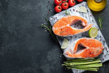 İki ham taze somon veya alabalık biftek, kireç, kekik ve Zeytinyağı karanlık bir arka plan ile omega-3 yağ açısından zengin. Sağlıklı ve diyet gıda. Üstten görünüm kopya alanı ile. Düz yatıyordu.