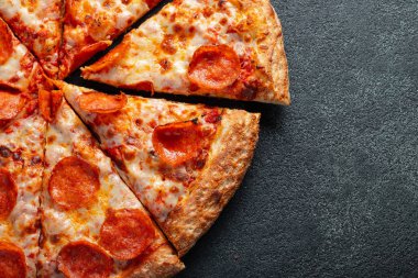 Lezzetli biberli pizza ve siyah beton arka planda domates fesleğeni. Acı biberli pizzanın en iyi manzarası. Metin için kopyalama alanı ile. Düz yatıyordu.
