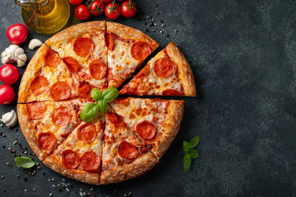 Lezzetli biberli pizza ve siyah beton arka planda domates fesleğeni. Acı biberli pizzanın en iyi manzarası. Metin için kopyalama alanı ile. Düz yatıyordu.