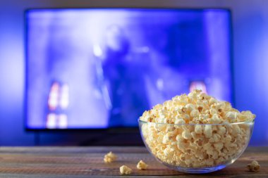 Bir cam kase patlamış mısır ve Uzaktan Kumanda Tv arka planda çalışır. Akşam rahat bir film veya Tv dizisi evde izlerken