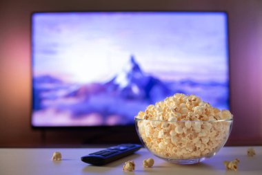 Bir cam kase patlamış mısır ve Uzaktan Kumanda Tv arka planda çalışır. Akşam rahat bir film veya Tv dizisi evde izlerken