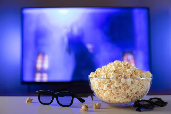 Szkła miskę popcorn, 3d okulary i zdalnego sterowania w tle telewizor działa. Przytulny wieczór, oglądając film lub serial Tv w domu — Zdjęcie stockowe