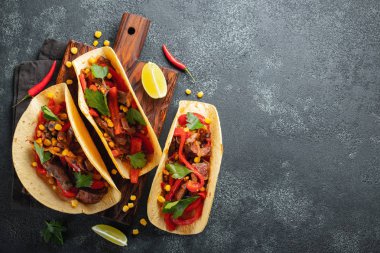 Et, sebze ve salsa Meksika Taco. Siyah arka plan üzerine ahşap tahta üzerinde Tacos al papazı. Kopya alanı ile üstten görünüm