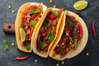 Et, sebze ve salsa Meksika Taco. Siyah arka plan üzerine ahşap tahta üzerinde Tacos al papazı. Üstten görünüm
