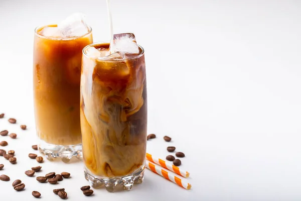 Es kopi dalam gelas tinggi dengan krim dituangkan di atas dan biji kopi. Minuman musim panas yang dingin dengan latar belakang putih dengan ruang fotokopi — Stok Foto