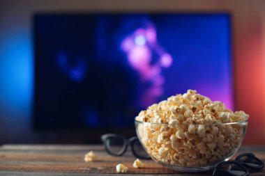 Bir cam kase patlamış mısır, 3d gözlük ve Uzaktan Kumanda Tv arka planda çalışır. Akşam rahat bir film veya Tv dizisi evde izlerken.