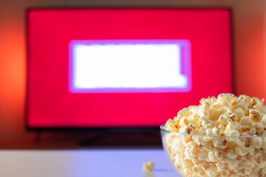 Bir cam kase patlamış mısır ve Uzaktan Kumanda Tv arka planda çalışır. Akşam rahat bir film veya Tv dizisi evde izlerken.