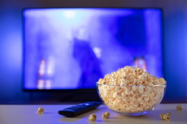 Bir cam kase patlamış mısır ve Uzaktan Kumanda Tv arka planda çalışır. Akşam rahat bir film veya Tv dizisi evde izlerken.