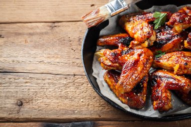 Fırında tavuk kanadı bir döküm Barbekü sosu içinde eski bir ahşap rustik masa üzerinde tava.