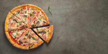 İtalyan Lokanta. Lezzetli sıcak pizza jambon ve dilimlenmiş ve kahverengi beton masaya servis petrol görünümü kapatın. Menü fotoğraf. Üstten görünüm kopya alanı ile. Düz yatıyordu.