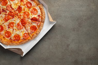 Kahverengi beton arka planda bir kutuda lezzetli pepperonili pizza. Acı biberli pizzanın en iyi manzarası. Metin için kopyalama alanı ile. Düz yatıyordu.