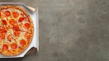 Kahverengi beton arka planda bir kutuda lezzetli pepperonili pizza. Acı biberli pizzanın en iyi manzarası. Metin için kopyalama alanı ile. Düz yatıyordu.