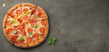 Fesleğenli kahverengi beton zemin üzerine lezzetli biberli pizza. Üstten görünüm sıcak biberli pizza. Metin için kopya yer ile. Düz yatıyordu.