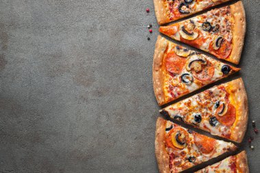 Dilimleri lezzetli taze pizza sosis sucuk ve peynir ile karanlık bir arka plan üzerinde kesmek. Üstten görünüm metin için kopya yer ile. Pizza siyah beton masada. düz lay.