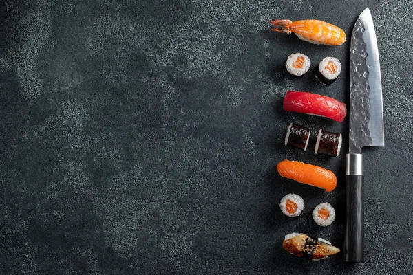 Different Sushi with Japanese knife on black stone slate background. Sushi on a table. Space for text. Top view. Sushi background. food frame