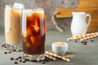 Krem üzerine dökülür ve kahve çekirdekleri ile uzun bir bardak buzlu kahve. Soğuk yaz içeceği kahverengi paslı arka plan üzerinde