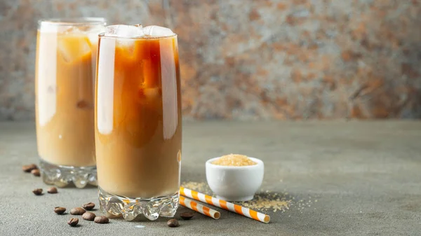 Café helado en un vaso alto con crema y granos de café. Bebida fría de verano sobre un fondo marrón oxidado con espacio para copiar —  Fotos de Stock