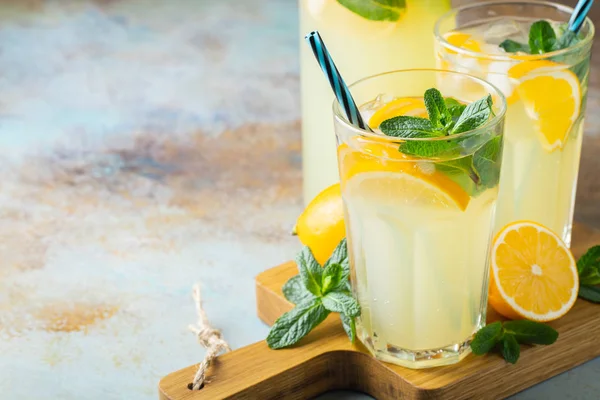 Due bicchieri con limonata o cocktail di mojito con limone e menta, bevanda rinfrescante fredda o bevanda con ghiaccio su sfondo blu rustico. Copia spazio — Foto Stock