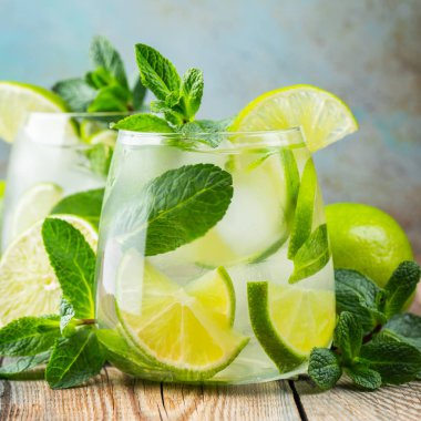 Rustik bir masada bir bardak buz küpleri ile iki Mojito kokteyl, seçici odak