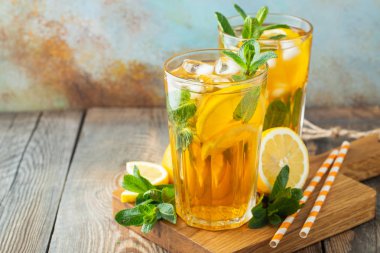 Ahşap bir rustik masada uzun bardak limon ve buz ile geleneksel buzlu çay. Kopyalama alanı ile