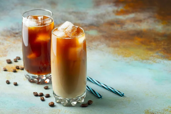 Кофе со льдом в высоком стакане со сливками и кофейными зёрнами. Холодный летний напиток на синем ржавом фоне с копировальным пространством — стоковое фото