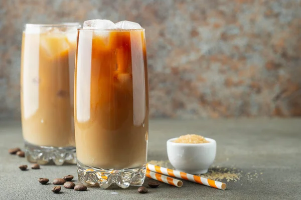 Кофе со льдом в высоком стакане со сливками и кофейными зёрнами. Холодный летний напиток на коричневом ржавом фоне с копировальным пространством — стоковое фото