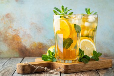Ahşap bir rustik masada uzun bardak limon ve buz ile geleneksel buzlu çay. Kopyalama alanı ile