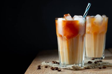 Üzerine dökülen kremalı uzun bir bardakta buz kahvesi, buz küpleri ve