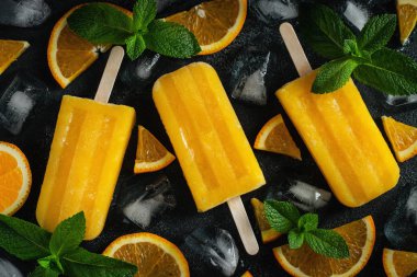 Koyu beton arka plan üzerinde portakal yapılmış parlak popsicle. Tatlı yaz ikramı. Üst te. Düz yatıyordu