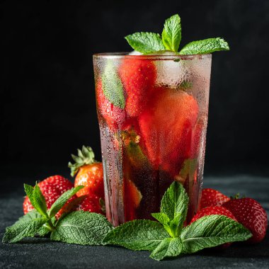 Siyah Masa arka planda cam üstünde buz, nane ve çilek ile taze limonata. Soğuk yaz içeceği. Berry kokteyl ile köpüklü gözlük