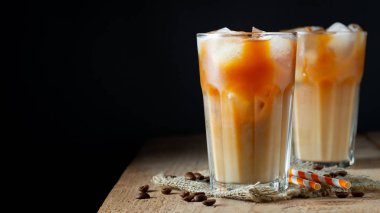 Üzerine dökülen kremalı uzun bir bardakta buz kahvesi, buz küpleri ve