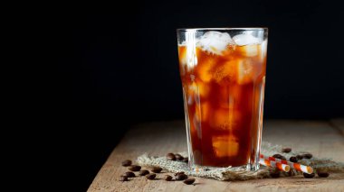 Üzerine dökülen kremalı uzun bir bardakta buz kahvesi, buz küpleri ve