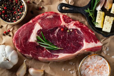 Bir kağıt üzerinde otlar ve baharatlar ile Çiğ ribeye sığır biftek. Üst te. Düz yatıyordu