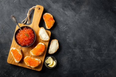 Kasede yakın çekim kırmızı havyar ve siyah arka plan üzerinde ahşap kesme tahtası üzerinde Sandwiches. Kopyalama alanı ile üst görünüm. Düz yatıyordu
