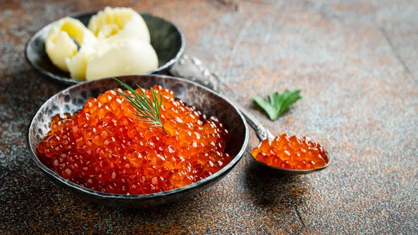 Delicious red caviar in black bowl on a dark concrete background. With copy space — Stock Photo, Image