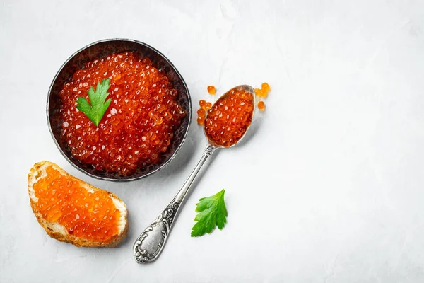 Delicious red caviar in black bowl on a light concrete background. Top view with copy space. Flat lay — Stock Photo, Image