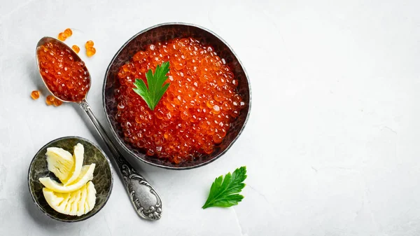 Delicious red caviar in black bowl on a light concrete background. Top view with copy space. Flat lay — Stock Photo, Image