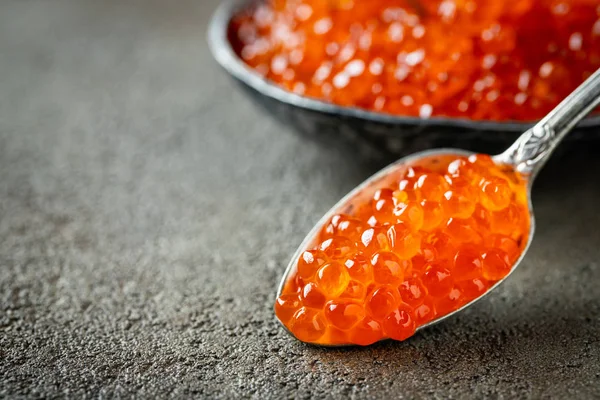 Close-up delicious red caviar in a spoon on a dark concrete background. With copy space — Stock Photo, Image