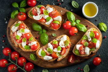Domates, mozzarella peyniri ve fesleğen dilimleme tahtasında. Geleneksel İtalyan aperatifi veya aperatifi, antipasto. Kopyalama alanı olan üst görünüm. Düz yatıyordu
